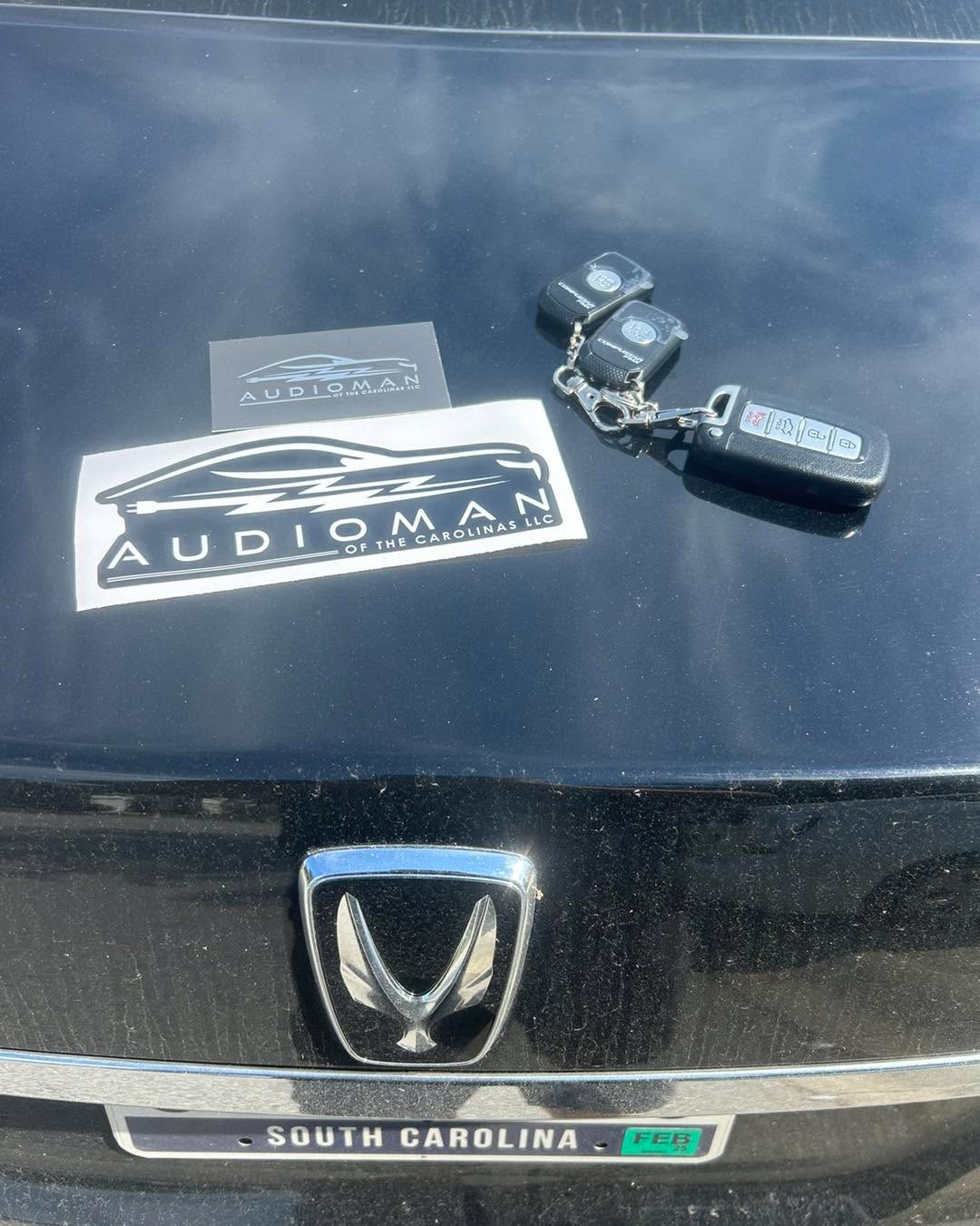 Keys and remotes laid on a vehicle with Audioman sticker